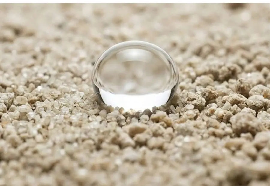 Illustrative water droplet beading on dry soil.